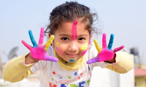 Cette image est l'illustration d'une jeune enfant montrant la peinture qu'elle a sur les mains