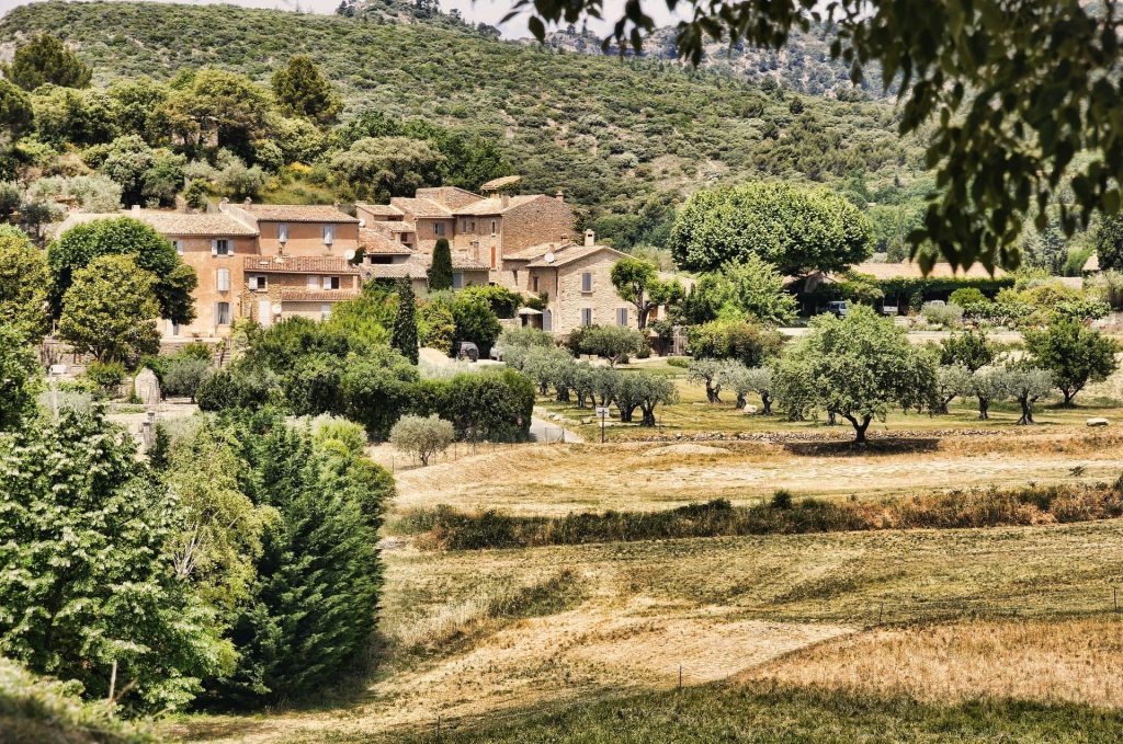 Cette image est l'illustration d'un village provencal au milieu des collines et des prairies